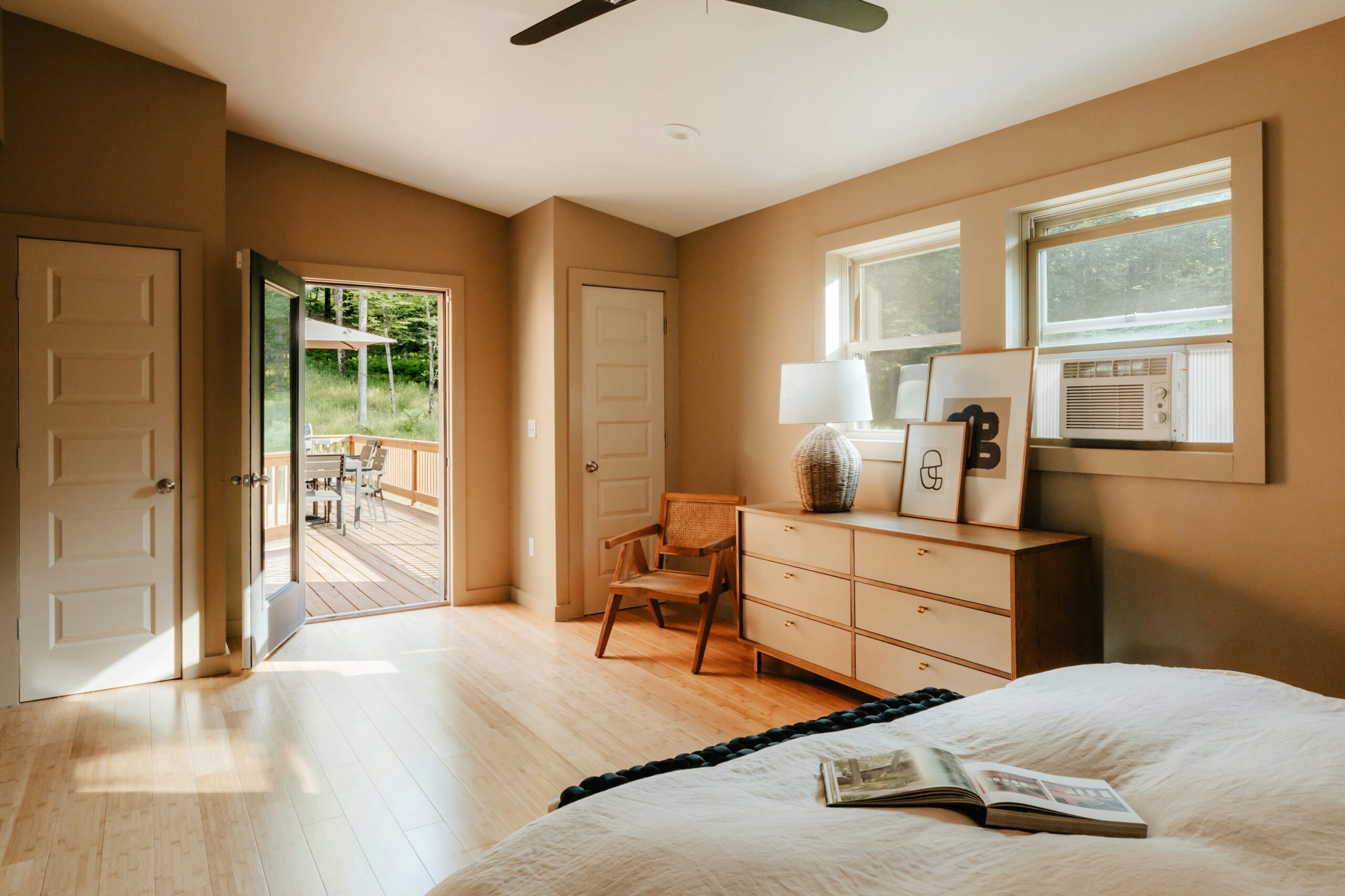 Minimalist bedroom with open floor space, warm light, simple wood furniture, and an airy uncluttered layout.