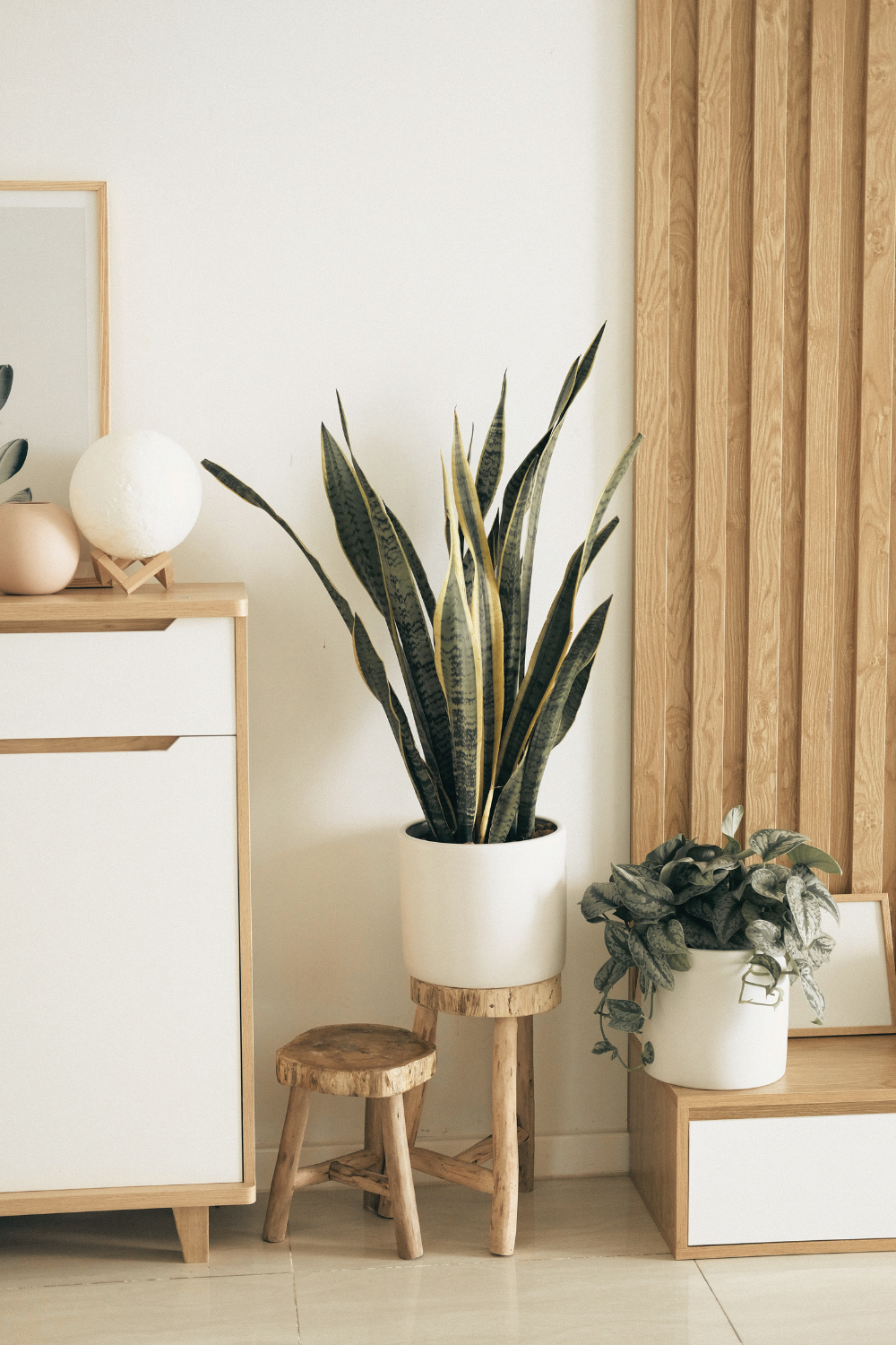 Warm wood nightstand beside a Japandi bed with simple intentional styling.
