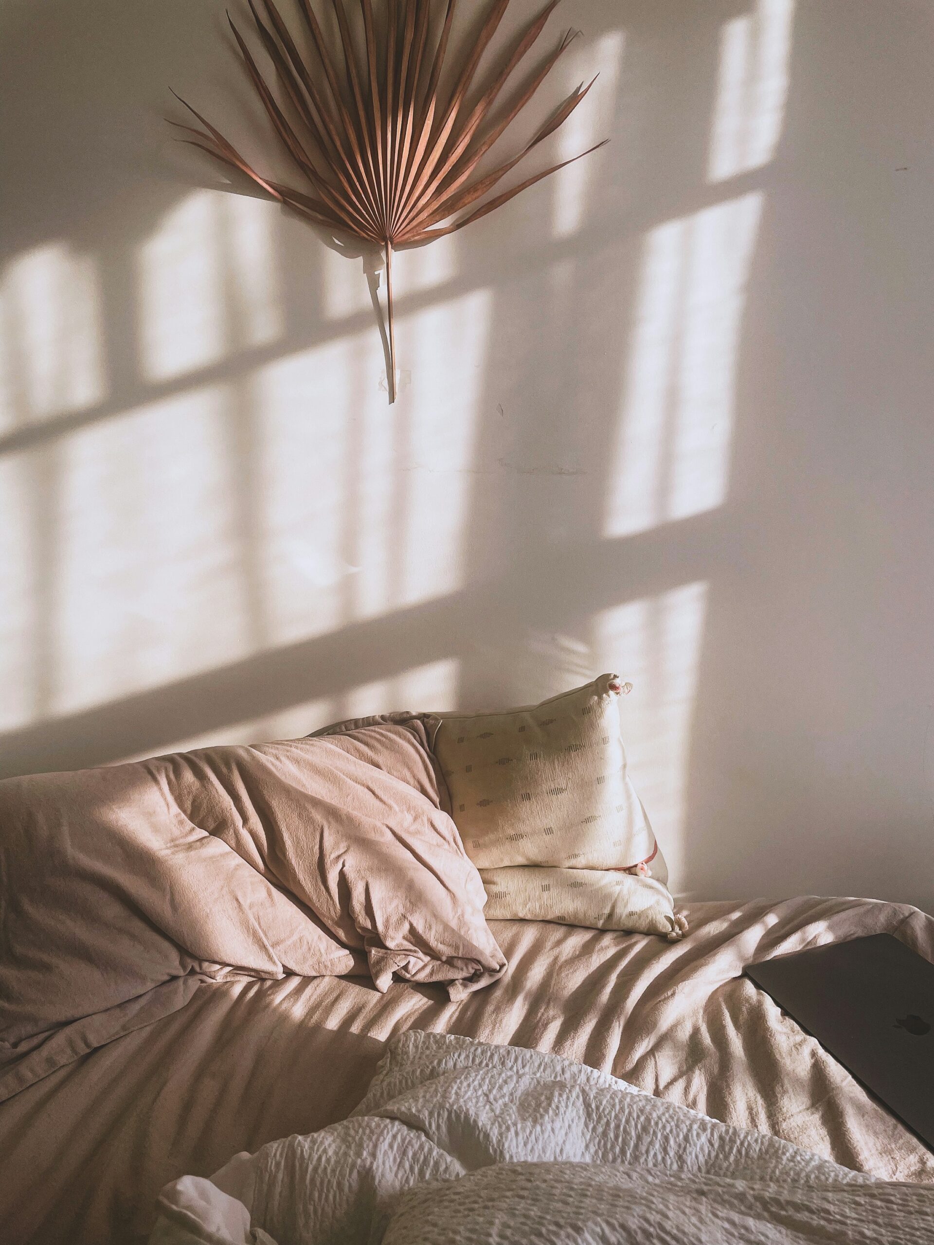 Soft neutral bedding and layered textiles creating a warm cozy bedroom atmosphere.