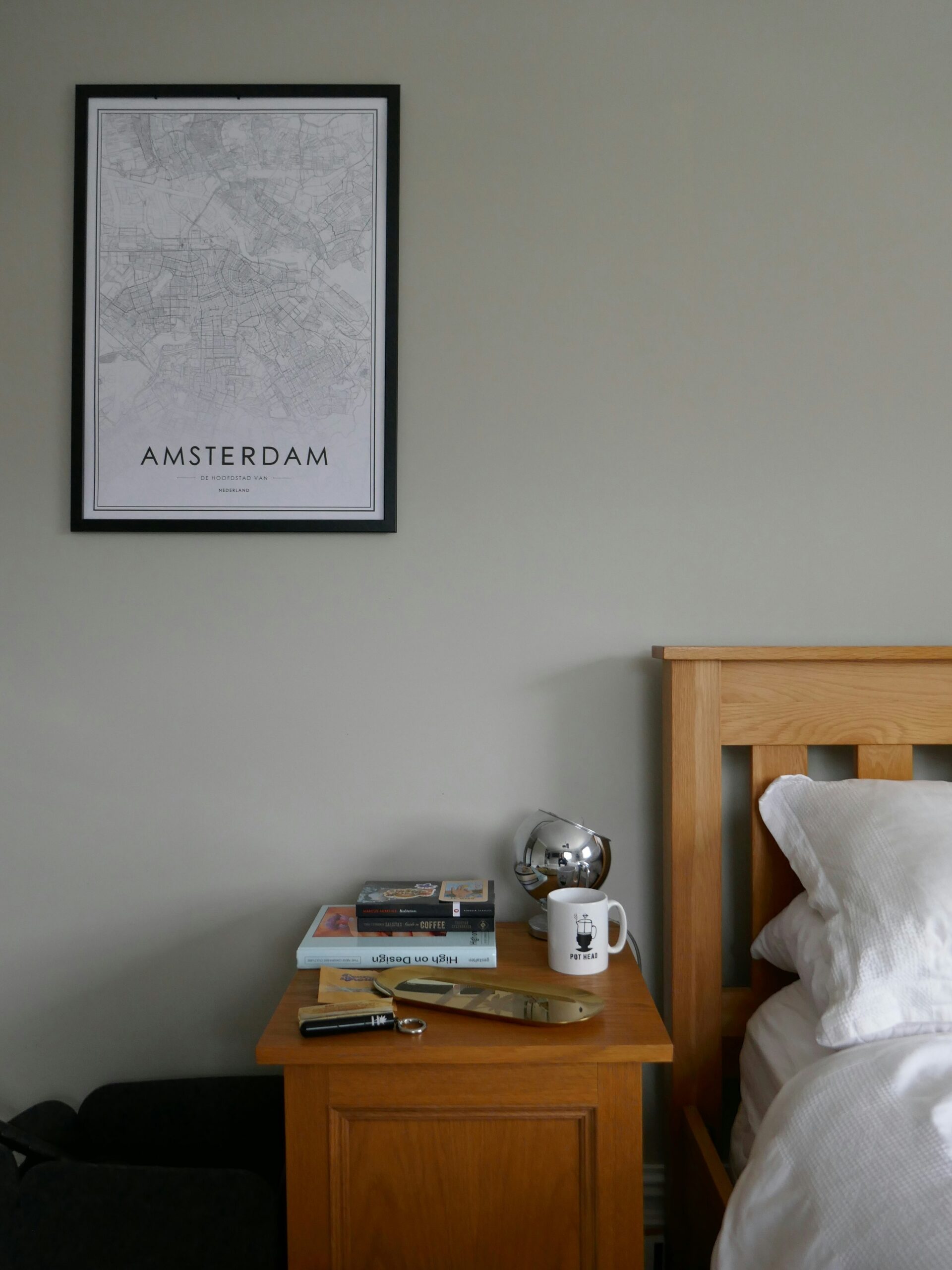 Nightstand with a few real-life objects and a relaxed bedroom setup that feels warm and gently lived in.