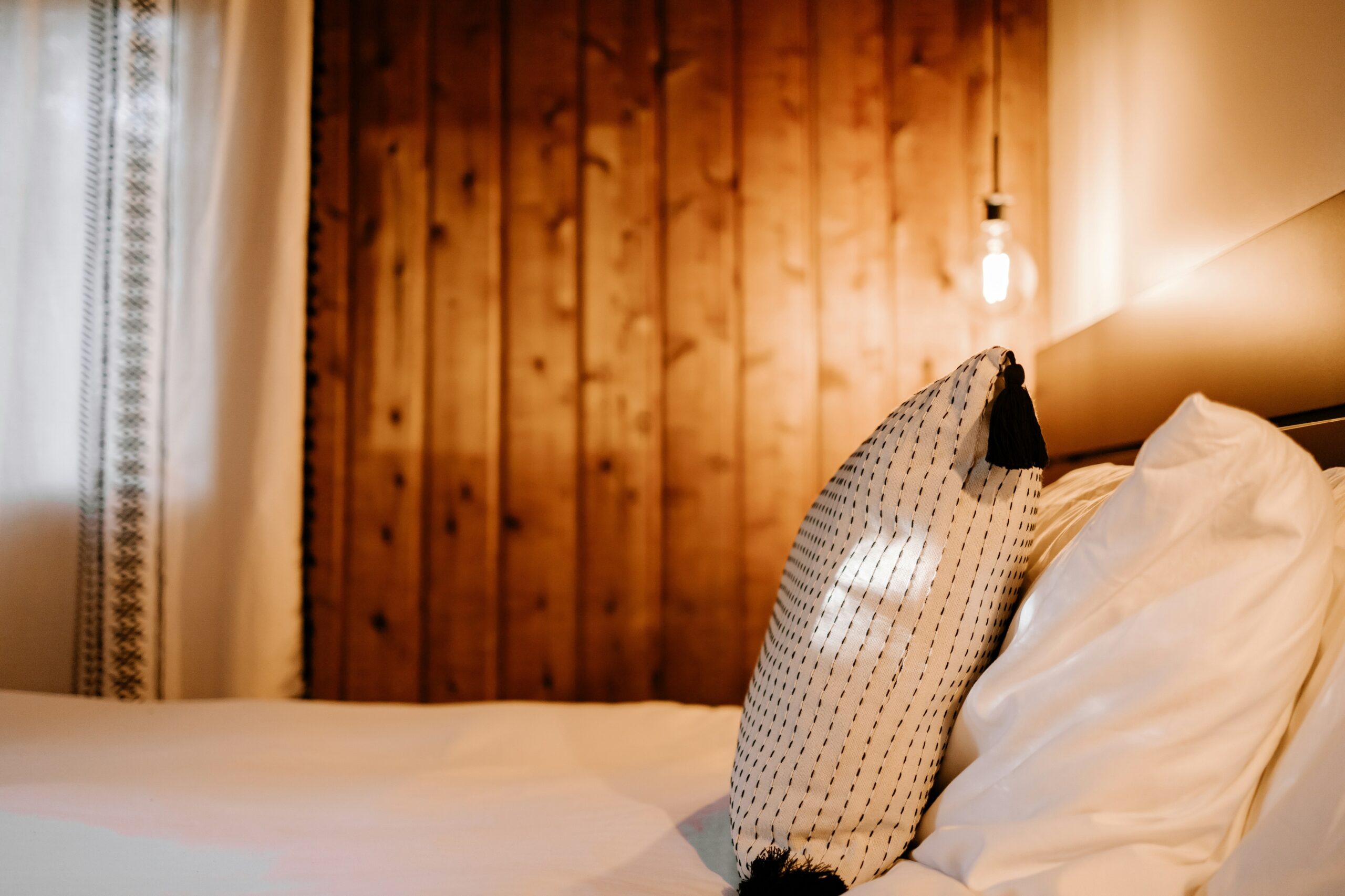 Warm wall light above a minimalist bedside setup adding a clean and cozy bedroom glow.