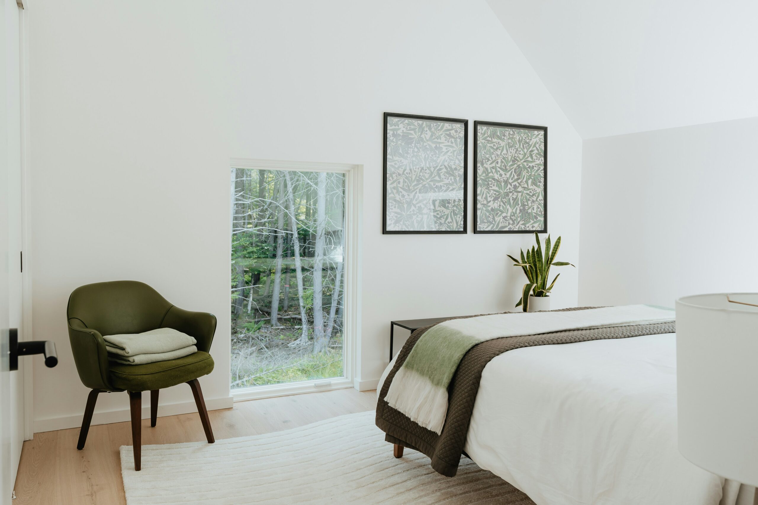 Soft sage green accent in a bright minimal bedroom with white walls and calm natural styling.
