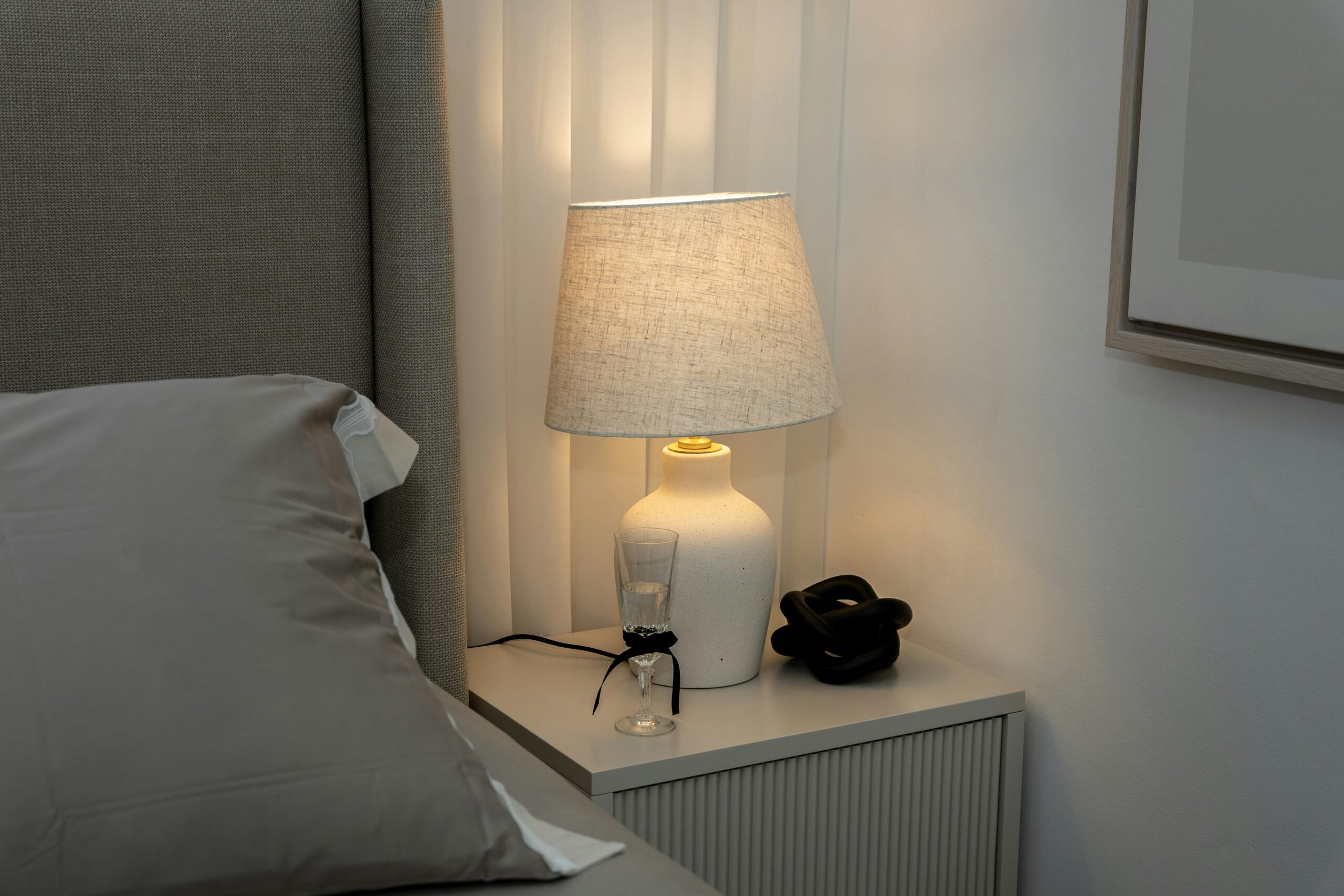 Warm bedside table lamp with a soft fabric shade creating a calm and gentle bedroom glow.